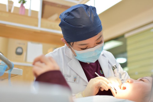 A dental hygienist looks into the mouth of a patient