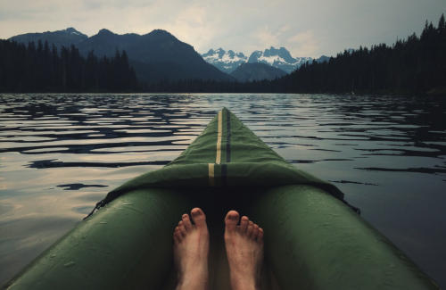 Person floating on a kayak in an alpine, wilderness lake.