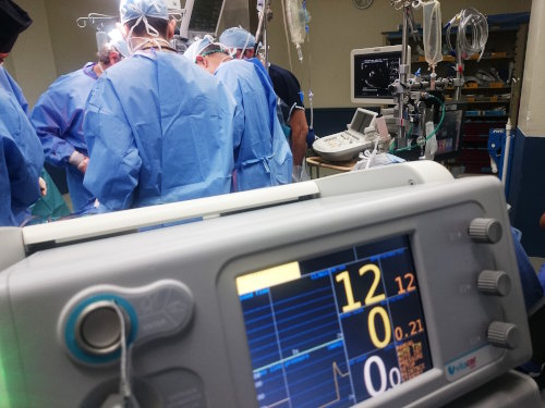 Doctors operating on a patient and surrounded with medical monitoring equipment