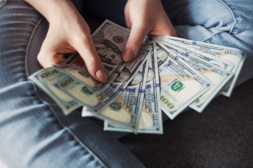 Girl fanning out a bunch of $100 bills